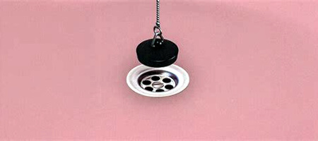 Pink basin, sink, or bathtub, with a black rubber stopper hovering over the silver drain. Linked to video for song "Black Hole."
